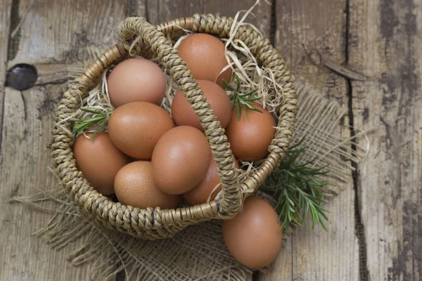 Huevos en una canasta sobre fondo de madera — Foto de Stock