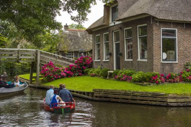 GIETHOORN, NETHERLANDS - 1 Ağustos 2017: Giethoorn 'daki bir kanalda tekne gezisinde bilinmeyen ziyaretçiler. Güzel evler ve bahçıvanlık şehri 