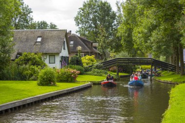 GIETHOORN, NETHERLANDS - 1 Ağustos 2017: Giethoorn 'daki bir kanalda tekne gezisinde bilinmeyen ziyaretçiler. Güzel evler ve bahçıvanlık şehri 