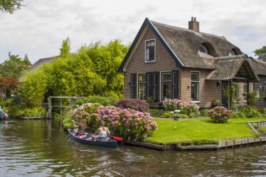 GIETHOORN, NETHERLANDS - 1 Ağustos 2017: Giethoorn 'daki bir kanalda tekne gezisinde bilinmeyen ziyaretçiler. Güzel evler ve bahçıvanlık şehri 