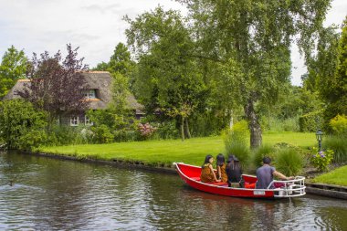 GIETHOORN, NETHERLANDS - 1 Ağustos 2017: Giethoorn 'daki bir kanalda tekne gezisinde bilinmeyen ziyaretçiler. Güzel evler ve bahçıvanlık şehri 