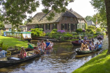 Giethoorn, Hollanda - 5 Ağustos 2015: Giethoorn 'da bir kanalda tekne gezisi yapan bilinmeyen ziyaretçiler. Güzel evler ve bahçıvanlık şehri 
