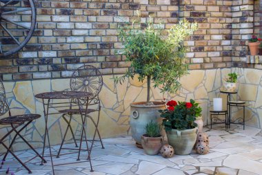 Akdeniz tarzında bahçede güzel bir yer. Izgaralı tuğla duvar ve çiçekli tencereler.