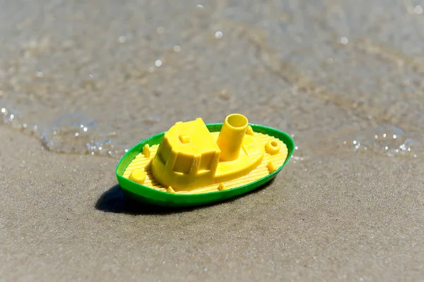 Barco de brinquedo na areia molhada do mar. Férias de verão no mar. Viagens de barco . — Fotografia de Stock