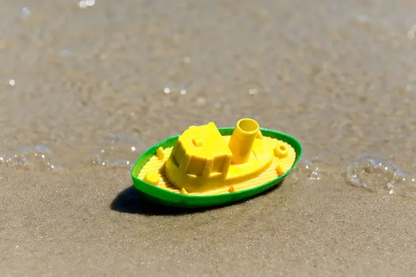 Toy boat in the wet sand of the sea. Summer holidays at sea. Boat trips. — Stock Photo, Image