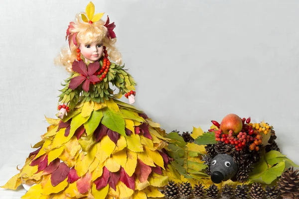 Boneca em um vestido feito de folhas de outono com uma tripulação de cones . — Fotografia de Stock