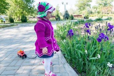 Çocuk küçük bir kız parkta blooming Iris kokusu içine çek. Bahar kadar basit.