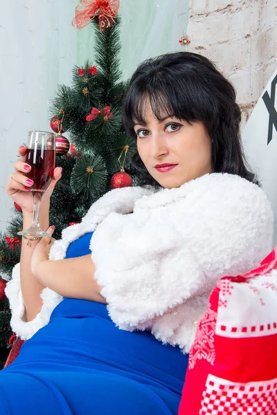 Noel süslemeleri bir kadeh kırmızı şarap ile arka plan üzerinde poz şirin esmer kız.