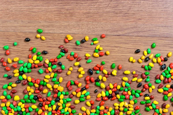 Kolorowe cukierki, rozrzucone na stole drewniane. — Zdjęcie stockowe