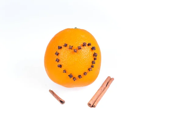Naranja brillante jugoso fresco decorado con un corazón de clavos y palos de vainilla sobre un fondo blanco . —  Fotos de Stock