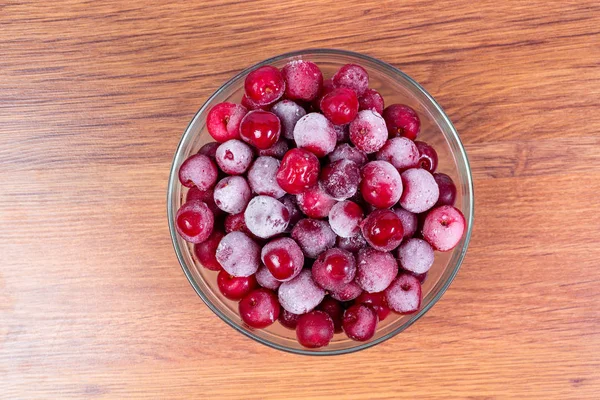Plate frozen red sweet ripe cherries on a wooden background. Harvesting of berries for the winter. — Stock Photo, Image