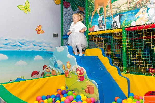 Liten söt flicka som leker i poolen med bollar. Födelsedag med roliga spel i stadens underhållning. — Stockfoto