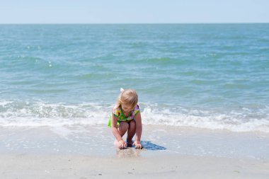 Bir çocuk, eğlenceli yaz aylarında deniz kıyısı üzerinde oynayan küçük bir kız.