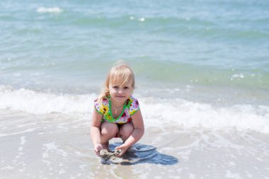 Bir çocuk, eğlenceli yaz aylarında deniz kıyısı üzerinde oynayan küçük bir kız.