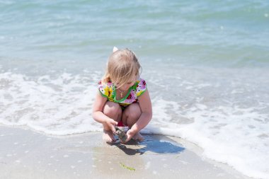 Bir çocuk, eğlenceli yaz aylarında deniz kıyısı üzerinde oynayan küçük bir kız.