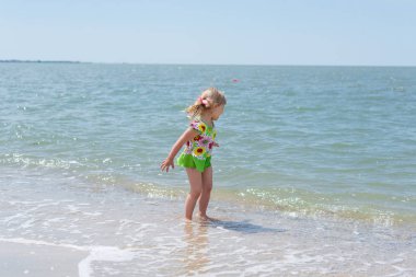 Bir çocuk, eğlenceli yaz aylarında deniz kıyısı üzerinde oynayan küçük bir kız.