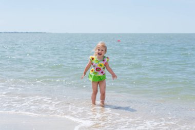 Bir çocuk, eğlenceli yaz aylarında deniz kıyısı üzerinde oynayan küçük bir kız.