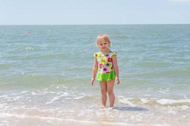 Bir çocuk, eğlenceli yaz aylarında deniz kıyısı üzerinde oynayan küçük bir kız.