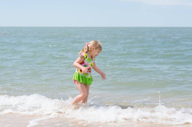 Bir çocuk, eğlenceli yaz aylarında deniz kıyısı üzerinde oynayan küçük bir kız.