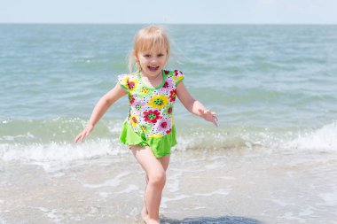 Bir çocuk, eğlenceli yaz aylarında deniz kıyısı üzerinde oynayan küçük bir kız.