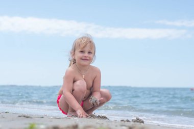 Bir çocuk, eğlenceli yaz aylarında deniz kıyısı üzerinde oynayan küçük bir kız.