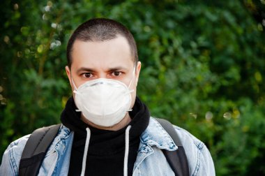 Yeşil ağacın yanında sırt çantalı bir adam.