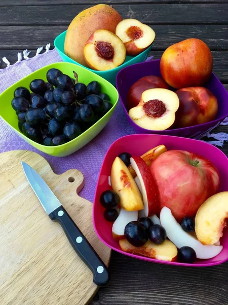 Frutas frescas con manzanas, nectarinas y uvas en cuencos coloridos — Foto de Stock