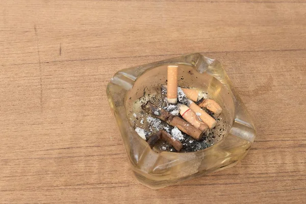 Сигарета з попільничкою на дерев'яному столі, багато фільтрувальної сигарети — стокове фото