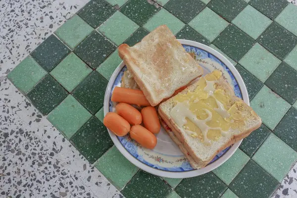 Roti panggang sarapan dengan telur goreng dan sosis di atas meja batu : — Stok Foto