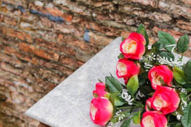 Plastik kırmızı güller ve beyaz ahşap tablo