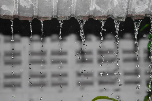 Niewyraźne, rozmycie ruchu kropla deszczu woda z dachu w nocy — Zdjęcie stockowe