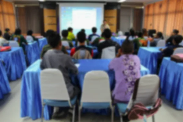 Focus vervagen, student zit in een klas met leraar voorzijde en projector diascherm — Stockfoto