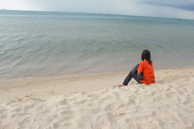 Deniz plaj ve görünüyor üzerinde oturan genç kadın