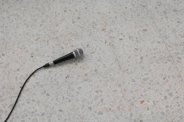 Mikrofon dynamisch mit seinem Kabel auf dem Boden Marmor poliert Stein Hintergrund — Stockfoto