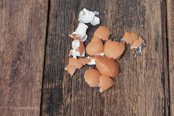 Casca do ovo espalhado no fundo da mesa de madeira — Fotografia de Stock