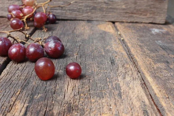 Uva vermelha fresca no fundo de mesa de madeira — Fotografia de Stock