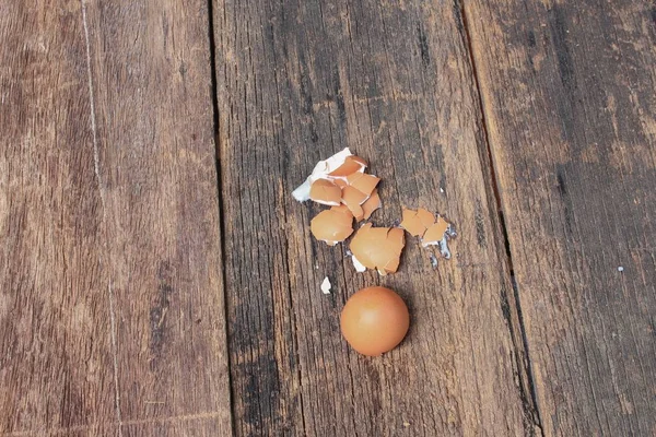 Casca do ovo espalhado no fundo da mesa de madeira — Fotografia de Stock