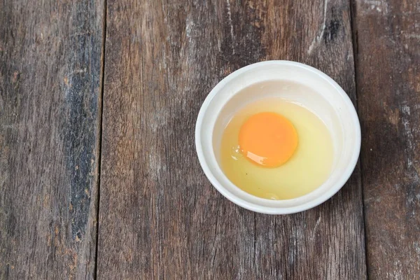 Raw egg in a bowl selective focus on wooden table — Stock Photo, Image