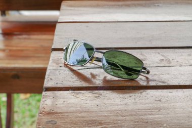Ahşap bir masa üzerinde siyah güneş gözlüğü.