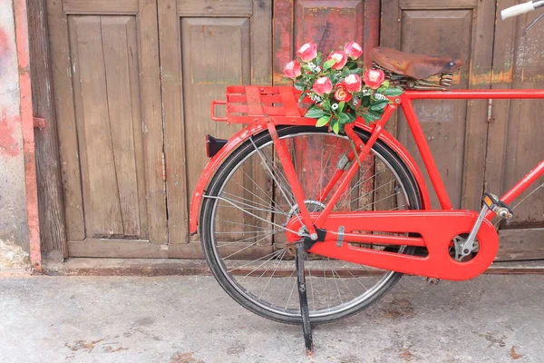 벽 나무 배경에 안장 빨간 자전거 클래식 빈티지에 꽃 — 스톡 사진