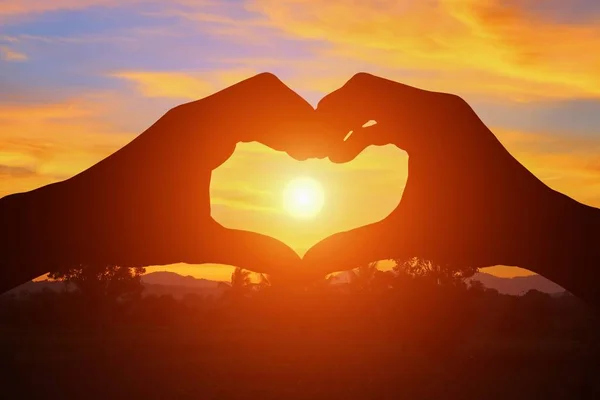 Hand forming silhouette a heart shape with  sunset  light — Stock Photo, Image