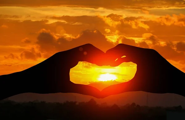 Hand forming silhouette a heart shape with  sunset  light — Stock Photo, Image