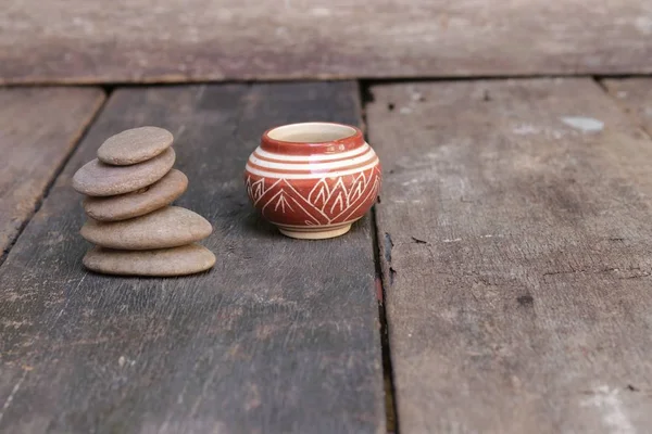 Piedra piramidal y jarra o tarro de esmalte de cerámica en el suelo de madera — Foto de Stock