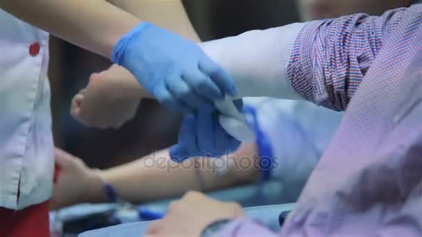 Доктор перевязывает руку пациенту бинтом — стоковое видео