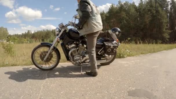 O homem vem a uma motocicleta, começa-a e parte — Vídeo de Stock