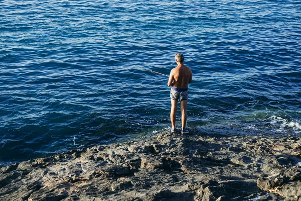 Eski balıkçı kayalık uçurum ve derin mavi deniz duruyor 