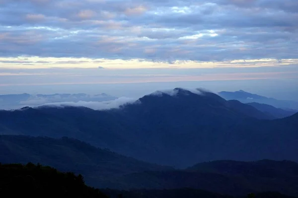Paisaje montañoso con oleada de niebla y cielo nublado oscuro en la t —  Fotos de Stock
