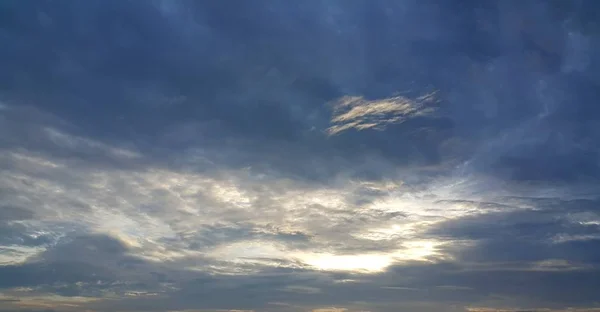 Céu escuro com nuvens brancas e luz solar — Fotografia de Stock