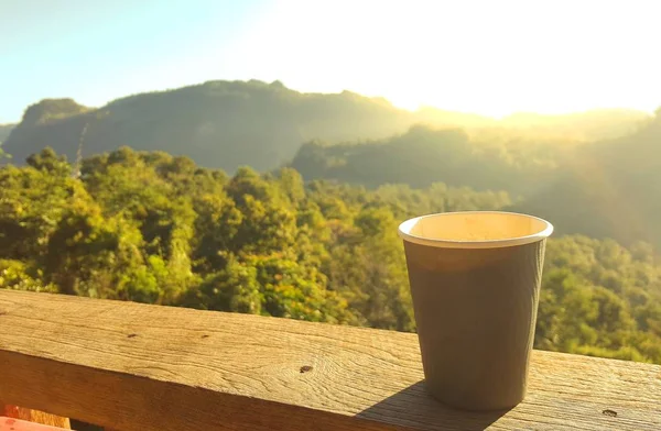 Kağıt kahve Kupası ahşap masa ve açık dağ ve sunl — Stok fotoğraf