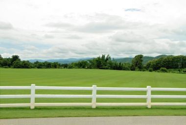 Beyaz çimento çit ve bulutlu gökyüzü ile Yeşil ovalar